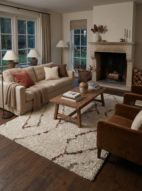 Tapis berbère crème Arles dans un salon avec cheminée et table basse en bois
