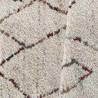 Gros plan sur les motifs berbères bordeaux, gris et caramel du tapis Arles