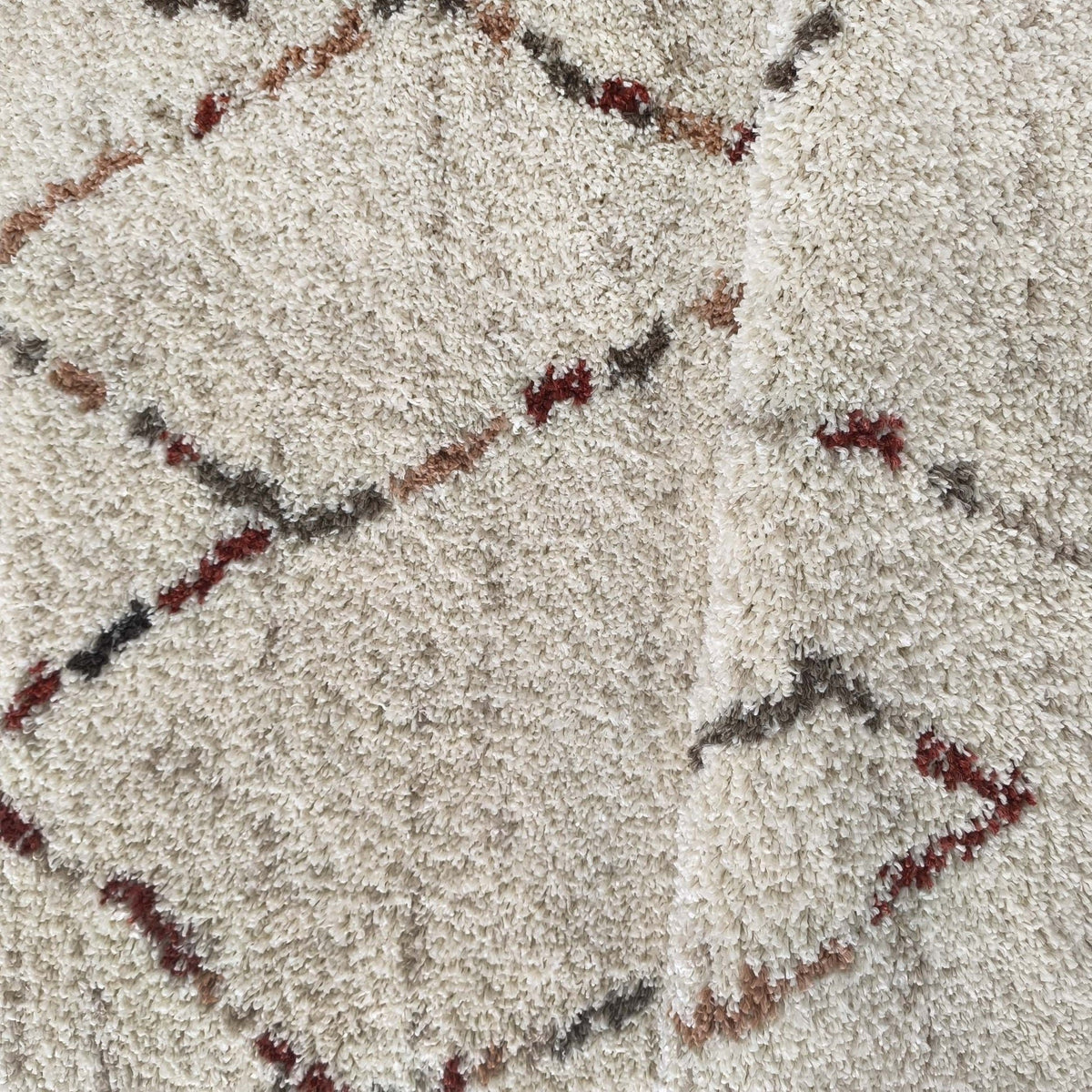 Gros plan sur les motifs berbères bordeaux, gris et caramel du tapis Arles