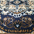 Gros plan sur le médaillon oriental crème, beige et noir du tapis Seine