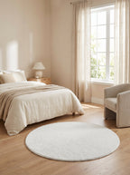 Tapis rond blanc cassé Craie dans une chambre lumineuse sur parquet clair
