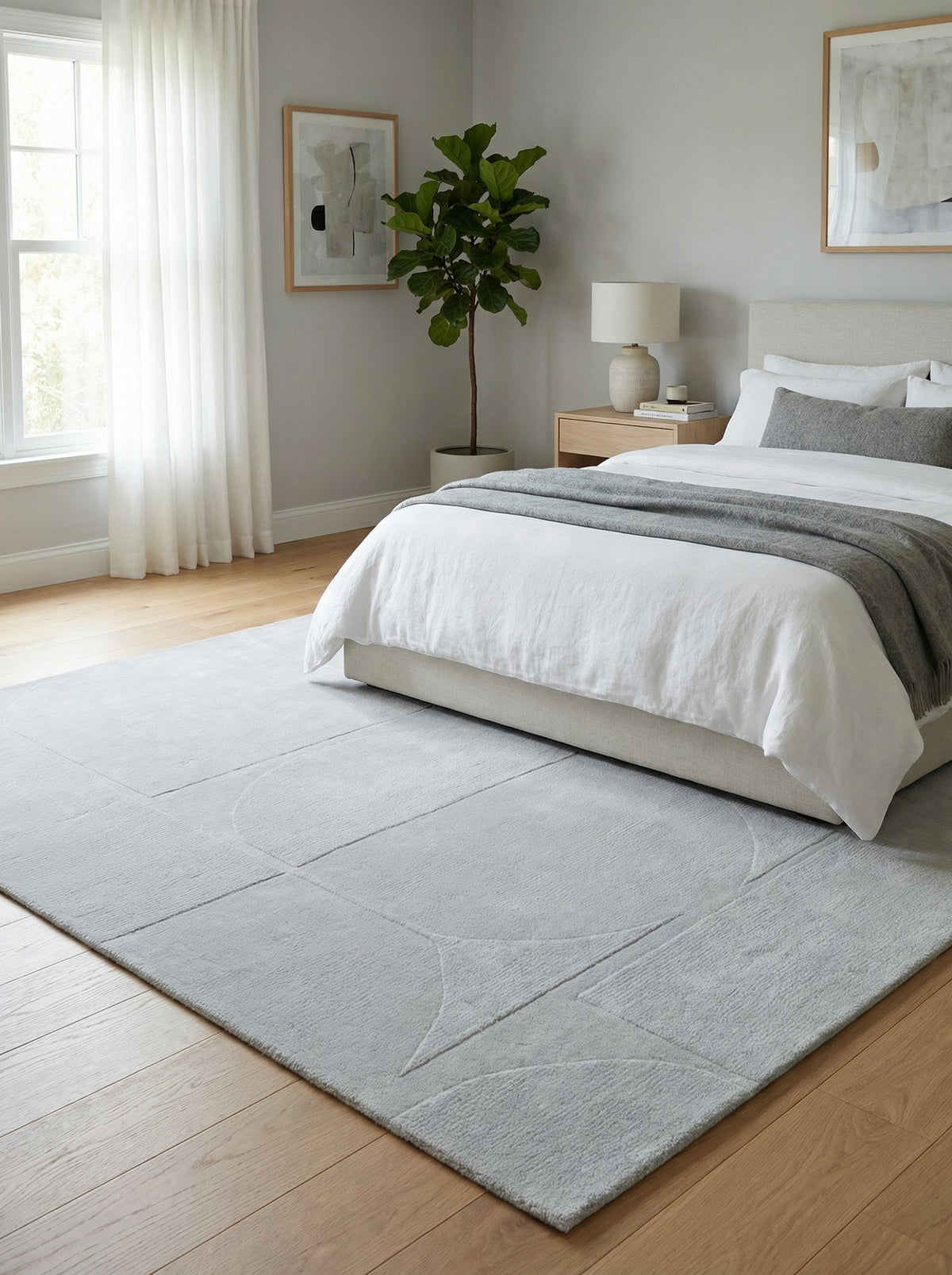 Tapis gris perle Nyons sous un lit dans une chambre claire sur parquet chêne