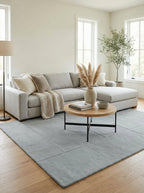 Tapis Nyons sous une table basse ronde devant un canapé d'angle gris clair