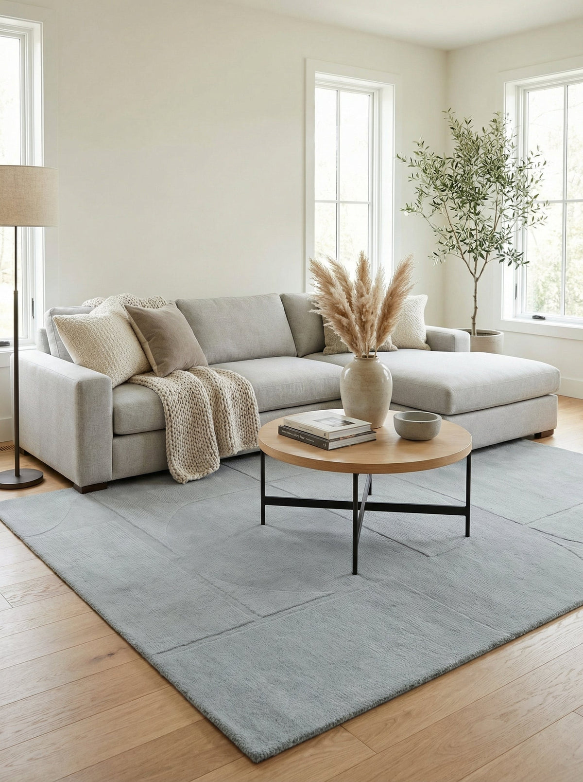 Tapis Nyons sous une table basse ronde devant un canapé d'angle gris clair